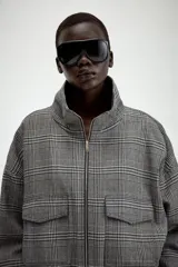 Chaqueta estilo bomber con estampado de cuadros, cuello subido, manga larga y cierre frontal con cremallera. Presenta bolsillos delanteros y bajo elástico.