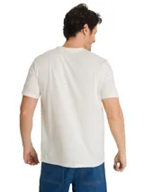 Remera de algodón color beige con cuello redondo y manga corta. Presenta un estampado gráfico frontal con maquinaria industrial y la palabra Caterpillar en un recuadro vertical.