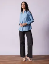 Camisa celeste de lyocell, con cuello a la base, escote en V y abertura central con botones. Tiene bolsillos aplicados en la parte delantera y mangas 3/4 regulables con presilla y botón.