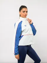 Campera deportiva Umbro del Club Nacional de Football, con diseño de bloques de color en azul marino y blanco. Presenta cuello alto, cierre frontal completo, bolsillos laterales y el escudo del club junto al logo de la marca en el pecho.