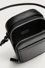 Bandolera vertical lisa de color negro, con compartimento principal con cierre de cremallera, bolsillo interior plano y asa de hombro ajustable.