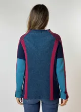 Sweater de punto grueso con cuello alto, diseño de bloques de color en azul marino, azul claro, fucsia y bordó. Presenta mangas largas y un corte holgado.