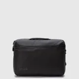 Mochila urbana de diseño minimalista en color negro, con compartimento principal con cierre y asa superior reforzada. Presenta el logo de la marca en la parte inferior frontal.