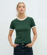 Remera baby tee verde oscura de manga corta, con ribetes blancos en el cuello redondo y en los puños.