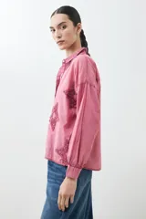 Camisa de corte clásico y manga larga en tono celeste claro, con diseño de estrellas aplicadas en tejido desflecado. Presenta cuello camisero y cierre frontal con botones.