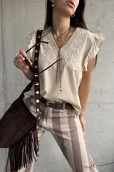 Musculosa de color beige con escote en V, mangas con volados y delicados bordados frontales.