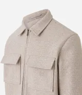 Campera pesada tipo trucker de polivelour color beige, con cuello camisero, cierre frontal por cremallera y dos bolsillos frontales con solapa en el pecho.