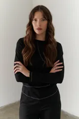 Remera negra de manga larga con cuello redondo y costuras decorativas en blanco.