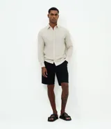 Camisa comfort de manga larga y cuello inglés, confeccionada en mezcla de lino y algodón. Presenta un diseño básico sin estampa con cierre frontal de botones.