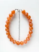 Collar de cuentas esféricas grandes con diseño marmolado en tonos marrones y beige, con cadena de extensión metálica plateada.