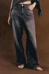 Jean de denim tiro alto con diseño baggy de corte ancho y relajado, color negro con efecto acid wash. Presenta cierre frontal con botón metálico y bolsillos clásicos.