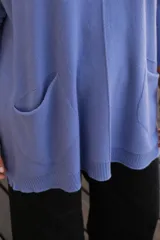 Sweater de punto color celeste, de corte holgado y largo, con mangas largas, cuello redondo y dos bolsillos frontales tipo parche.