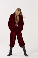 Pantalón de terciopelo color borgoña, de tiro alto, con cintura elástica en la espalda, cierre frontal, bolsillos laterales y piernas anchas.