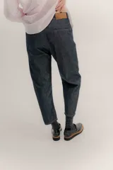 Pantalón de denim oscuro con tiro bajo y calce relajado. Presenta un cierre frontal con botones a la vista y costuras en contraste.