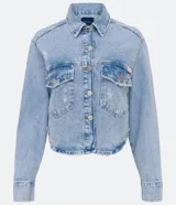 Camisa cropped de jeans celeste con cuello solapa, abotonada al frente, con bolsillos delanteros, desgastes y barra redondeada.
