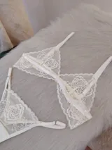 Conjunto de lencería compuesto por un bralette triangular de encaje floral y una bombacha tipo tanga a juego con detalles de encaje y tiras ajustables.