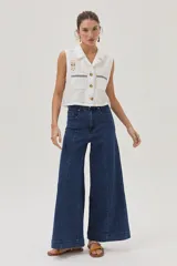 Blusa blanca de lino con cuello camisero, sin mangas, cierre frontal con botones y bordados en el frente.