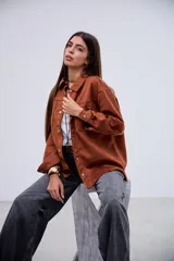 Sobrecamisa de gamuza color terracota, con cuello clásico, cierre frontal de botones metálicos, bolsillos en el pecho y mangas largas con puños abotonados.