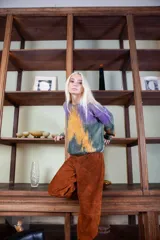 Sweater de lana merino tejido artesanalmente, con diseño pintado a mano que combina tonos violeta, verde y naranja. Presenta cuello redondo, mangas largas y un corte holgado y cómodo.