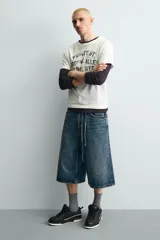 Zapatilla deportiva de estilo urbano con cordones, confeccionada en una combinación de piezas de cuero sintético. Presenta un diseño con detalles en contraste, suela con volumen bicolor y tirador en el talón.