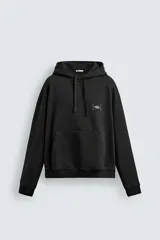 Sudadera negra de corte relajado con capucha ajustable, manga larga y bolsillo frontal tipo canguro. Presenta un pequeño estampado a contraste en el pecho y acabados en rib en puños y bajo.