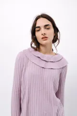 Buzo de tejido acanalado color lila, con cuello redondo decorado con dos volados y mangas largas con tres volados pequeños en los puños.