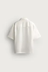 Camisa negra de manga corta, confeccionada en lino con corte relaxed fit, cuello bowling y cierre frontal de botonadura.