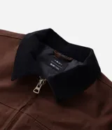 Campera masculina modelo trucker confeccionada en sarga de algodón. Presenta cuello de terciopelo en contraste, cierre frontal con cremallera, manga larga y bolsillo con cremallera en el pecho.