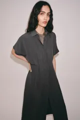 Vestido midi de corte camisero color gris, confeccionado con mezcla de lyocell y lino. Presenta cuello solapa, manga corta, pliegues en la cintura y cierre frontal con botones ocultos.