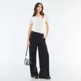 Pantalón de corte ancho y tiro medio, color negro, con detalle de cintura elástica visible estilo bóxer y bolsillos laterales.