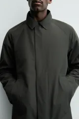 Gabardina impermeable de corte regular fit en color verde militar, con cuello solapa, manga larga con puño ajustable con botones a presión y bolsillos de vivo en la cadera. Cierre frontal con cremallera oculta por solapa con botones a presión.
