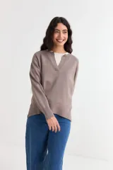 Sweater de tejido de punto color topo, con cuello abierto en V, mangas largas con puños acanalados y diseño con tajos laterales en el ruedo.