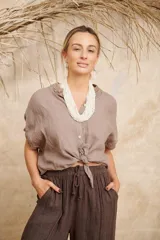 Camisa marrón de lino con cuello mao, manga corta y cierre frontal con botones.