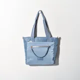 Bolso tote celeste de tela con bolsillo frontal con cierre y doble asa corta.