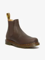 Bota Chelsea Dr. Martens 2976 YS Crazy Horse, color marrón, fabricada con cuero Crazy Horse desgastado. Presenta paneles elásticos laterales, costuras amarillas Goodyear y una tira de tela amarilla con el logo de la marca en la parte trasera.
