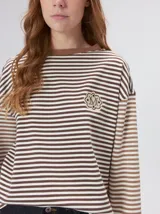 Remera de manga larga con diseño a rayas horizontales en tonos celestes y blancos en el cuerpo, y mangas a rayas azul marino y blancas. Presenta cuello redondo en color azul marino, logo bordado en el pecho y calce holgado.