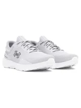 Championes de running Under Armour modelo Charged Escape 4, color blanco con detalles en gris claro. Presentan parte superior de malla técnica transpirable, contrafuerte externo en el talón para mayor sujeción y mediasuela con tecnología Charged Cushioning para una amortiguación óptima.