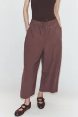 Pantalón de tiro medio con corte estilo balloon, cintura elástica ajustable con cordones, bolsillos laterales ocultos y bolsillos de plastrón en la parte trasera.