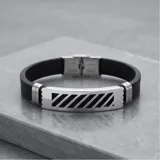 Pulsera masculina con diseño moderno, compuesta por una placa central de acero inoxidable con detalles calados y bandas laterales de goma negra.