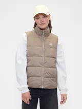 Chaleco puffer Gap color beige, con cuello alto, cierre frontal completo y logo de la marca aplicado en el pecho.