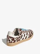 Championes Adidas Samba OG con diseño de estampado animal print de vaca en tonos marrón y blanco. Presenta las icónicas tres bandas laterales en blanco, cordones en color celeste y suela de goma natural.