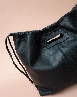 Cartera tipo tote de cuero color bordó, con diseño fruncido en los laterales y abertura central integrada como asa. Presenta una silueta flexible y espaciosa, ideal para uso diario.