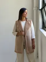Chaleco largo de gamuza sintética color beige, con interior y bordes de corderito sintético al tono. Diseño abierto sin botones.