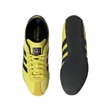 Championes urbanos Adidas modelo Tokyo, color amarillo con las icónicas tres tiras laterales en negro. Presentan un diseño de perfil bajo con suela de goma negra y detalles en gamuza en la zona de los cordones y el talón.