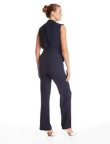 Enterito de crepe color azul marino, con torso plisado sin mangas y cuello alto. Presenta corte en la cintura con lazo de ajuste y pantalón de pierna recta con bolsillos funcionales.