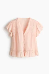 Blusa rosada de tejido liviano con alforzas e inserciones de encaje, escote en V pronunciado, cierre frontal de botones y mangas mariposa cortas con terminación fruncida en el ruedo.