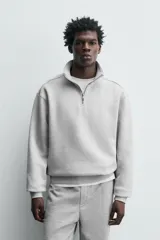 Sudadera roja de corte regular, con cuello alto y cierre frontal de cremallera. Manga larga y terminaciones en rib.