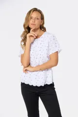 Blusa blanca con estampado floral negro, de corte recto y manga corta.