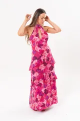 Vestido largo fucsia con estampado abstracto, cuello halter con abertura en forma de lágrima y volados en la falda.