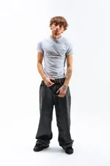 Pantalón de denim azul desgastado, corte mega baggy con piernas anchas y bolsillos traseros grandes. Presenta un bordado dorado en estilo gótico en el bolsillo trasero izquierdo.